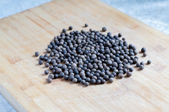 A pile of black pepper on a wooden cutting board