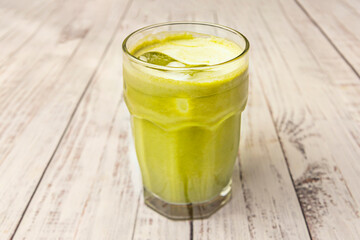 Close-up of hands holding a glass of iced matcha tea with herbs and lemon at an outdoor cafe, a moment of summer refreshment