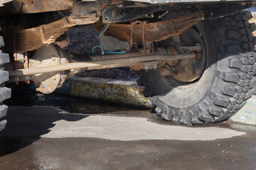 A truck with a large tire and a large suspension. The suspension is made of metal and is covered in rust