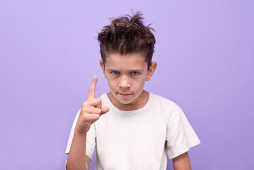 Boy pointing warning gesture on lilac background expressing emotion and communication. A young boy emphasizes something or strictly indicates that this is not allowed
