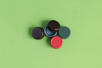 A green background with four different colored caps on it. The caps are red, blue, green, and brown
