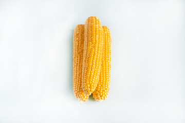 Three yellow corn cobs are on a white background