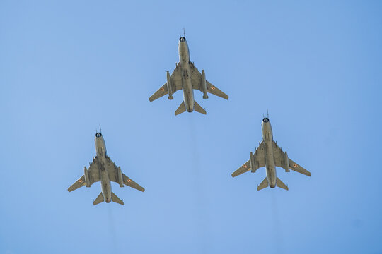 Formation flight of Sukhoi Su-22 jets soaring through a clear blue sky during a military display in early summer