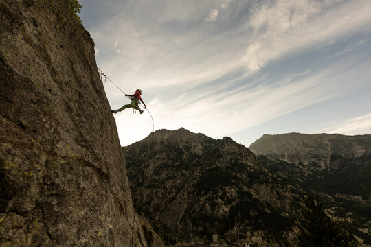 A man is climbing a rock wall with a red and white outfit