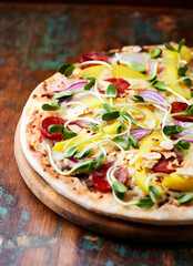 Pizza with chorizo ​​sausage, mozzarella cheese and yellow pepper. Rustic wooden background. Soft focus.	