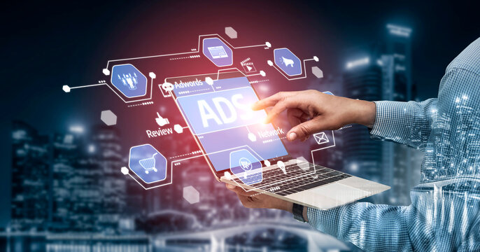 A person interacts with a laptop showcasing advertising icons and analytics in a modern urban setting, symbolizing digital marketing and creative strategies. Tessel