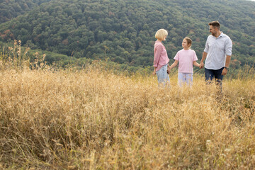 Family enjoying time together in a scenic landscape with lush green hills during the day
