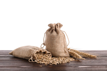 Rye grains, spikelets and burlap bags on wooden table against white background