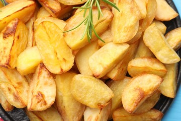 Tasty baked potatoes with rosemary on light blue table, top view