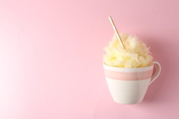 Tasty cotton candy with straw in cup on pink background, top view. Space for text