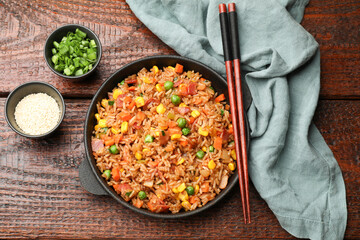 Delicious fried rice in baking dish served on wooden table, flat lay