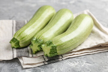 Fresh ripe zucchinis on grey textured table, closeup
