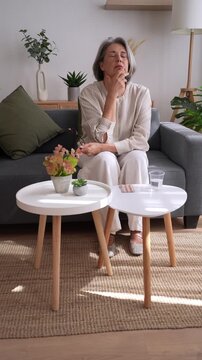 Senior woman taking medicine at home