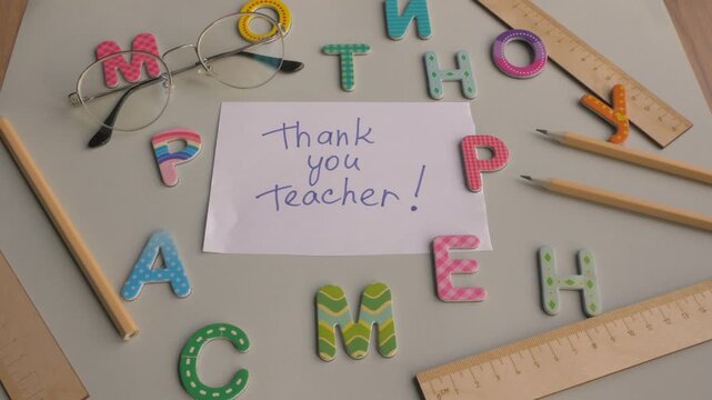 Colorful letters and glasses surround a handwritten note expressing gratitude for teachers, showcasing a heartfelt appreciation scene. Happy teacher's day 