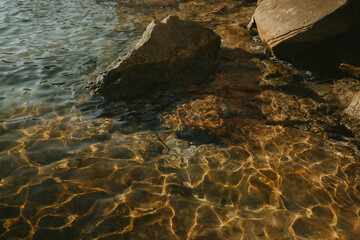 Golden Sunlight Reflections on Shallow Water with Rocks in Ibiza