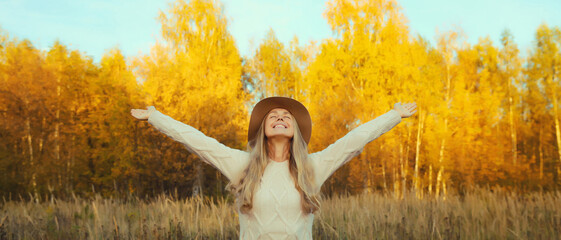 Happy smiling young woman in autumn park, joyful girl enjoying warm sunny weather, nature