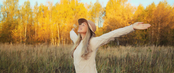 Happy smiling young woman in autumn park, joyful girl enjoying warm sunny weather, nature
