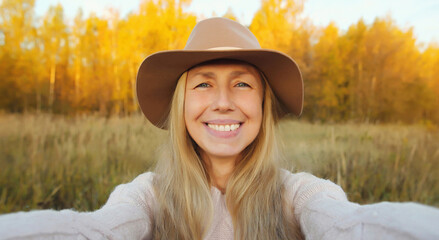 Portrait of happy smiling mature woman taking selfie with phone, stylish middle aged female in park
