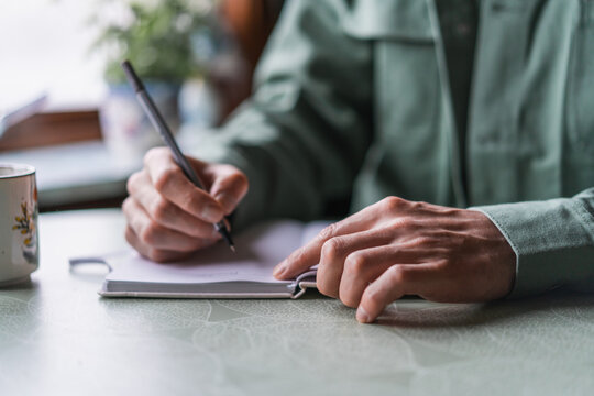 Man Writing in Notebook by Window