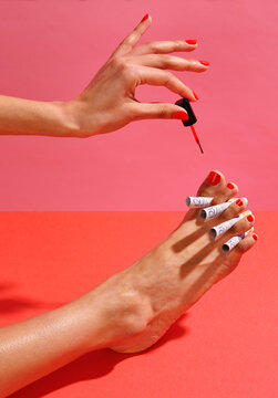 Woman painting red toenails with &pound;20 notes as toe separators
