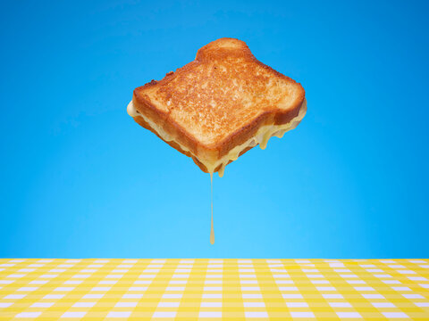 Cheese sandwich floating against a blue background above a tablecloth