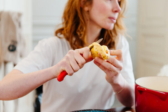 Red hair woman peeling potatos