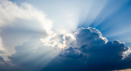 Sunbeams breaking through dramatic dark and light clouds in blue sky light rays