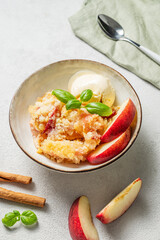 Peach crumble or cobbler with vanilla ice cream scoops and cinnamon on a plate on a light background