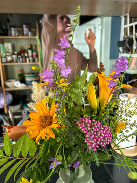 Bright Flower Arrangement on Kitchen Counter With Person in Background