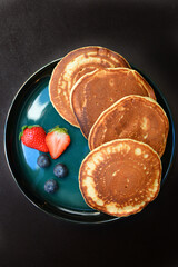 Yummy Pancakes with strawberries and blueberries on a plate.