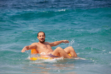 Happy kids have fun in sea surf on beach. Joyful couple of children on inflatable ring ride on breaking wave. Travel lifestyle, swimming activities in family summer camp. Vacations on tropical island