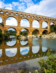Fototapeta premium Ancient stone aqueduct bridge over a calm river, reflections