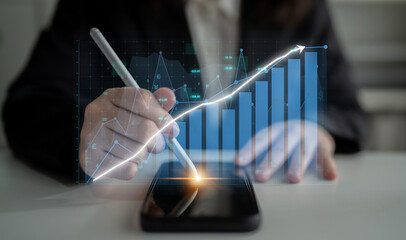 A business professional interacts with a smartphone displaying holographic financial charts, illustrating data analytics and growth strategies in a modern office. Impute