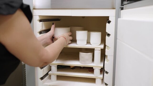 Ceramist placing pottery in kiln for firing