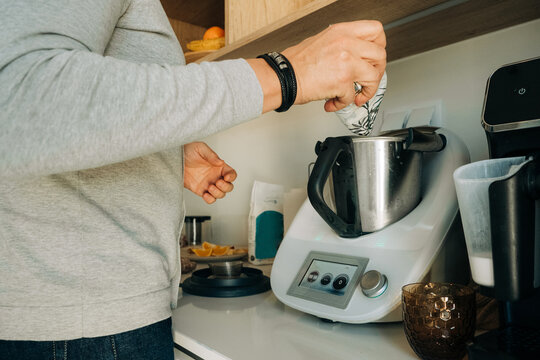 Man Adding Ingredients to Electric Food Processor in Kitchen