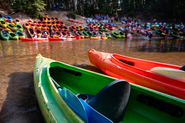 Riverbank with many kayaks on both sides, kayak base ready for rafting