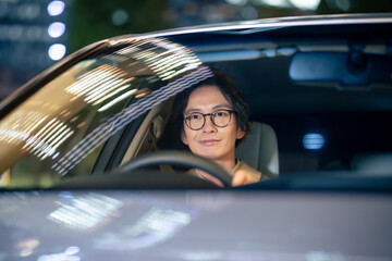 夜に車を運転する男性