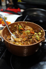 guiso de pisto de varios ingredientes, aguacate, tomate, sepia, carne en una fuente de barro