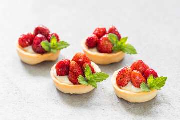 Small Round Strawberry tartlets. Light gray background. Close up	