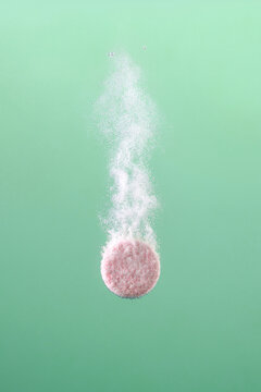 Effervescent Tablet Dissolving in Water Against Green Background