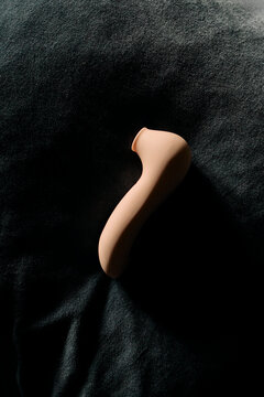 Pink vibrator laying on a dark blue pillow