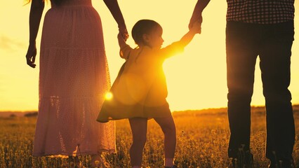 silhouette cheerfully playing girl sunset. child with parents cheerfully jumps runs sun. happy family life together. summer time family vacation. child kid with mother father walk hand park. outside