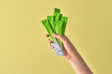 A hand holds multiple green and white snack packets against a so