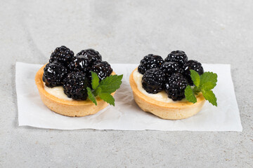 Two Vegan Small blackberry tartlets. Light gray background. Close up
