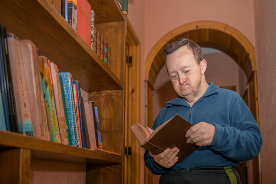 Man with Down syndrome Reading a Book in a Hallway 