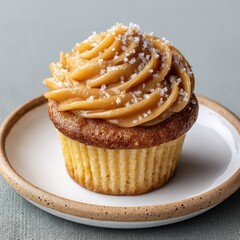 A delicious cupcake, perfectly frosted with creamy caramel and a sprinkle of sea salt, presented on a white plate. A sweet treat ready to enjoy. side view, solid background