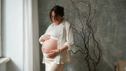 Beautiful maternity portrait of a young, glowing expectant mother in a cozy home setting