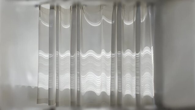 Flowing undulations and gentle gradients of pale window drape creating soft blurred shadow effects and abstract curved form designs on isolated backdrop