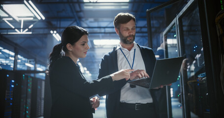 Two server specialists talk and work in data center.