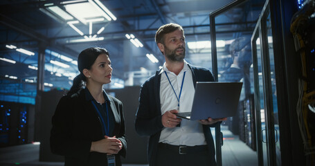 Two server specialists talk and work in data center.